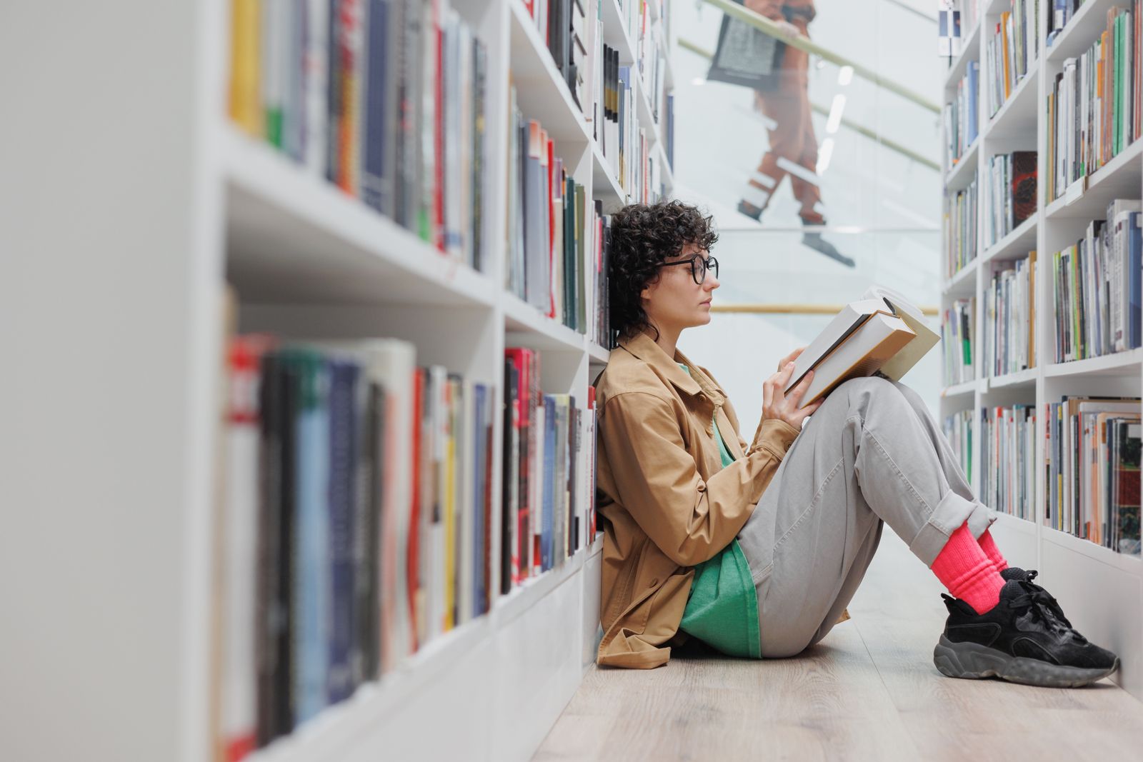 Woman sitting on the floor reading a book in a library - IMD Business School